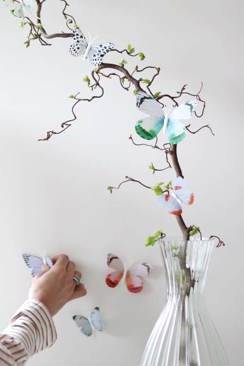 decoratie vlinders op witte muur en tak met hand